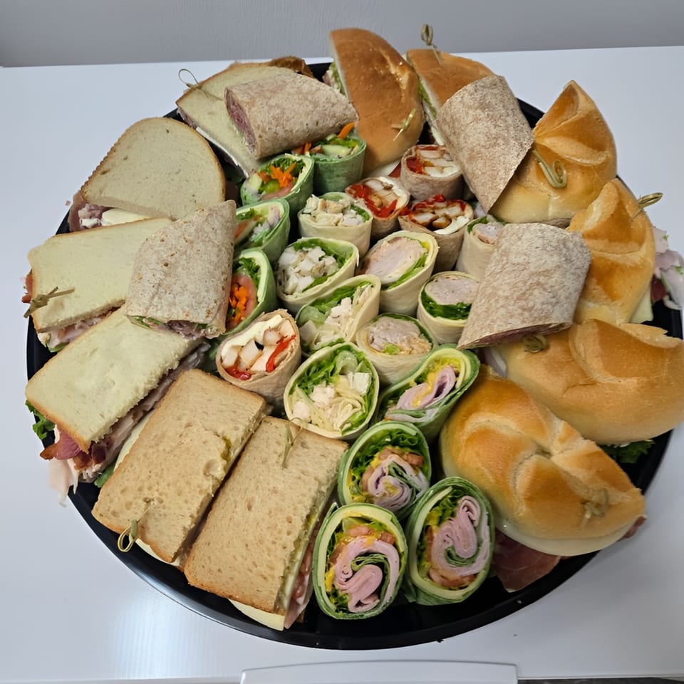A catering platter from Trento Gourmet Deli Catering filled with assorted sandwiches, wraps, and rolls.